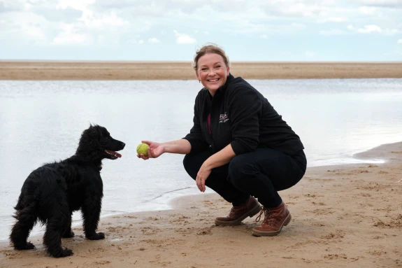 Jo Page on a beach in Norfolk with a black dog
